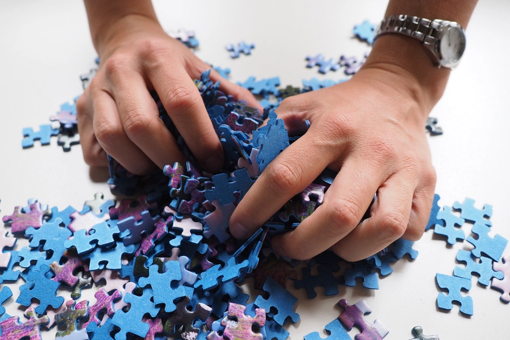 Hands sorting a pile of blue jigsaw puzzle pieces
